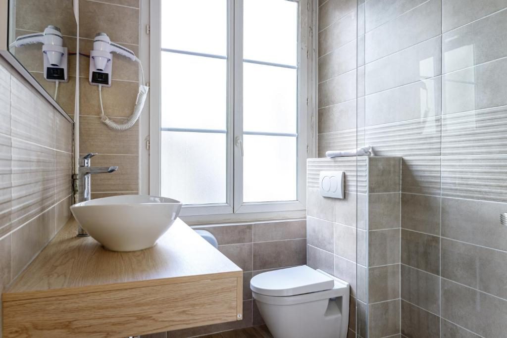 Salle de bain rénovée avec vasque, fenêtre et douche vitrée